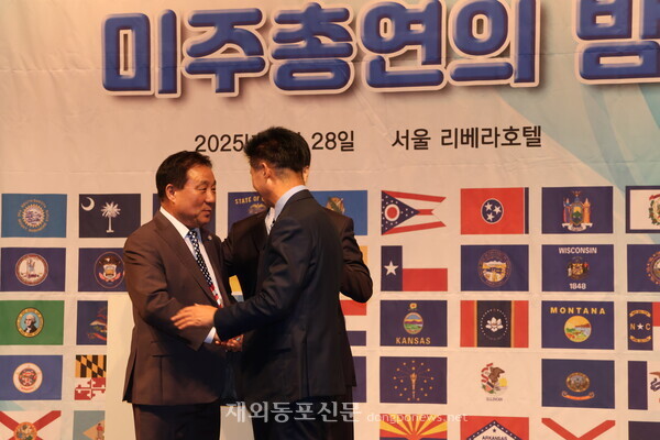 서정일 김만중 차기 회장 후보가 "미주총연의 화합"을 다짐하는 의미로 포옹에 앞서 악수하는 모습.
