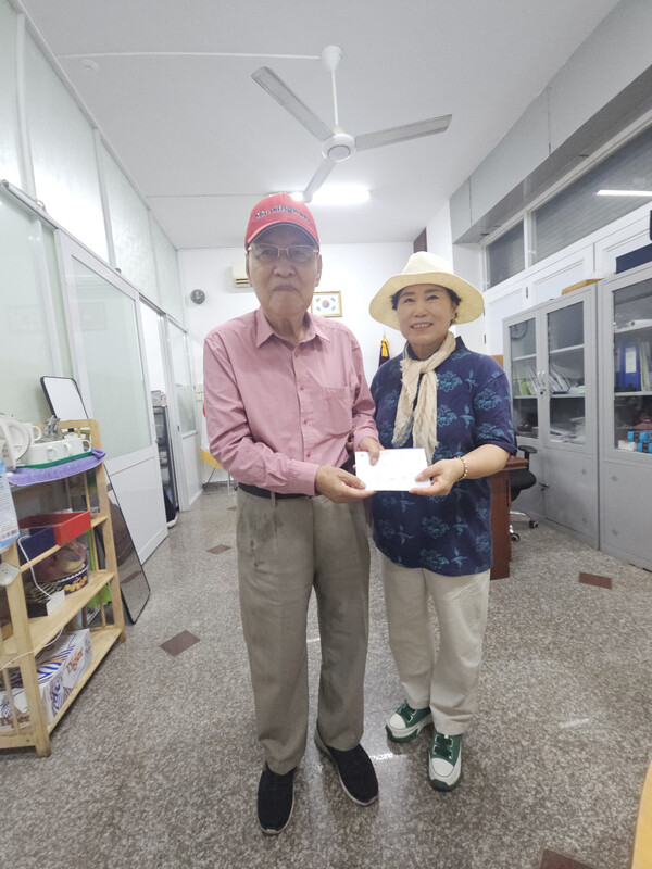 주옥자 회장이  심장병으로 현지병원에서 큰 수술을 받은 90세 김성찬 노인(좌)에게 위로금을 전달하고 있다다