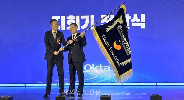 월드옥타 신원칠 신임 톈진지회장이 양성철 지회장에게서 지회기를 건네받는 모습.  