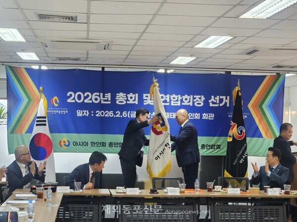 윤희 아시아한인회총연합회 회장이 김기영 차기 회장 당선인에게 연합회기를 전달하는 모습. [아총연]