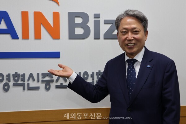2만5000여 경영혁신 중소기업을 회원사로 둔 메인비즈협회 김명진 회장이 서울 숭인동 협회 사무국 내 메인비즈협회 CI 앞에서 포즈를 취한 모습. [황복희 기자]  