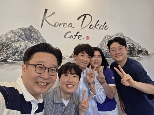 서준범 작가가 그려서 카페에 기증한 ‘독도 수묵 벽화’를 배경으로 출연진들이 기념촬영한 사진.